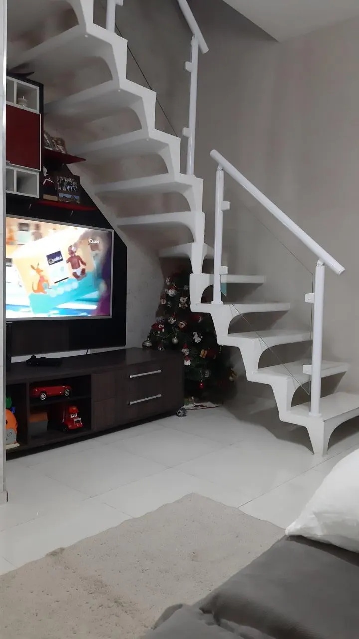 Sala com rack de TV e escada para o andar de cima