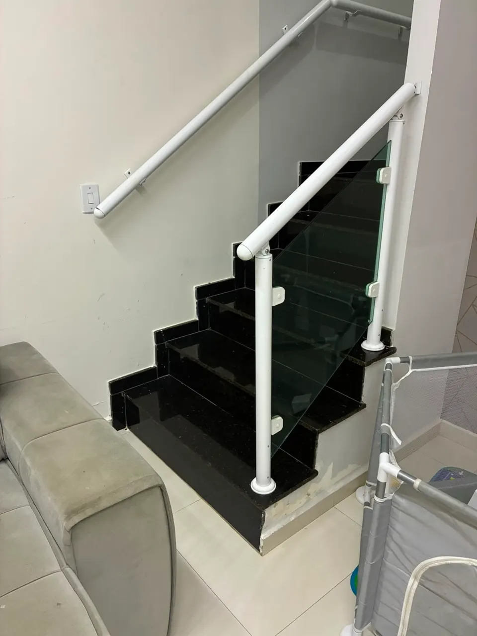 Escada com degraus pretos e guarda-corpo de vidro