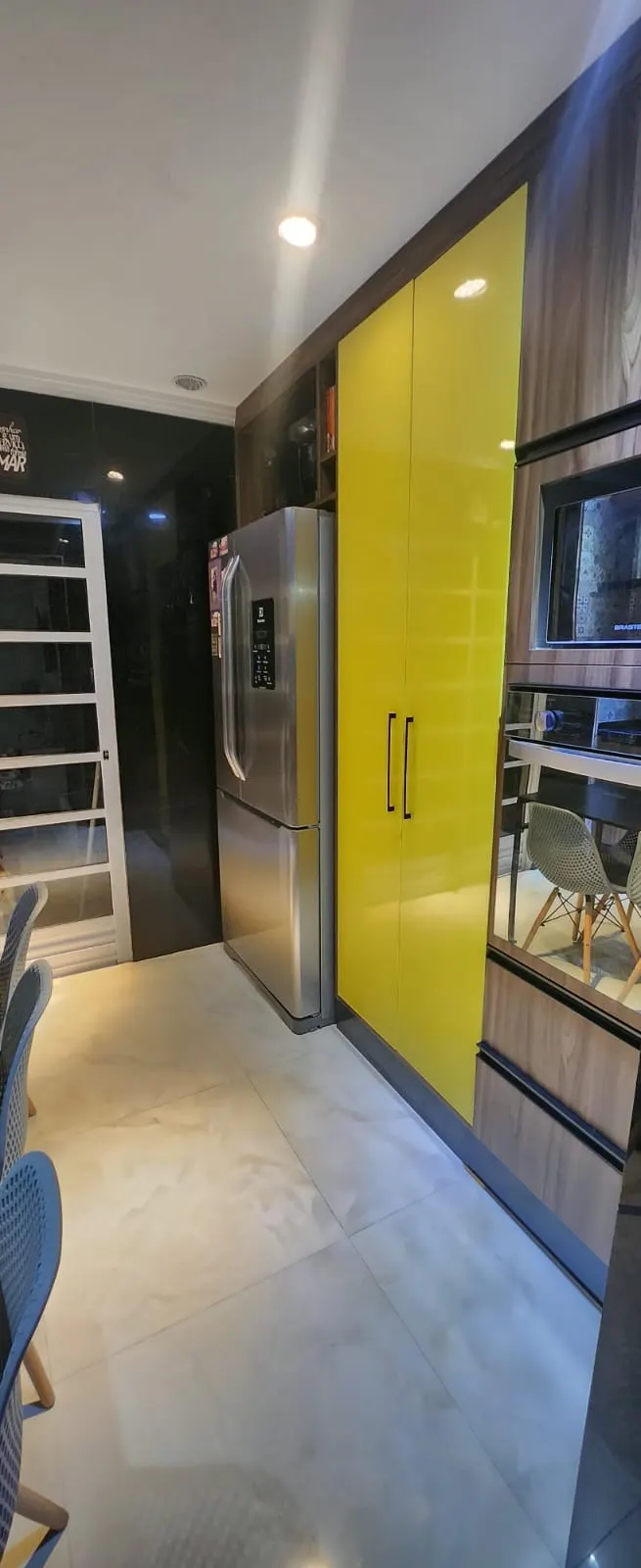 Cozinha com geladeira e armário amarelo